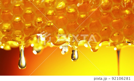 Honey dripping from honey comb on golden background. Honey dripping from honey comb on golden background. 92106281