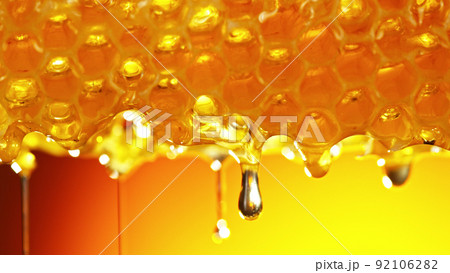 Honey dripping from honey comb on golden background. Honey dripping from honey comb on golden background. 92106282