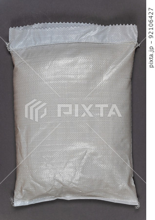 A full white bag against a gray background. Closed bag with food or other products. Top view. Copy space for text and design elements. A full white bag against a gray background. Closed bag with food or other products. Top view. Copy space for text and design elements. 92106427