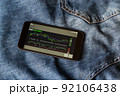 Stock market and cryptocurrency chart on your smartphone screen, which includes an up trend and a down trend. Stock market investment. The smartphone lies on top of the blue jeans. 92106438