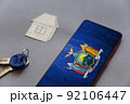 Smartphone, door keys, and paper house on gray background. New York State flag on screen of your device. Buying or renting homes. Moving to live in New York State. Selective Focus. 92106447