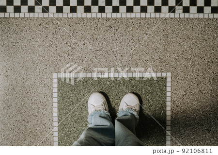 Top view of woman legs in jeans and white sneakers on pattern tile floor. Copy space, teenager 92106811