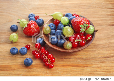 Berries mix in in a heart shaped bowl spilled on rustic wooden table Berries mix in in a heart shaped bowl spilled on rustic wooden table 92106867