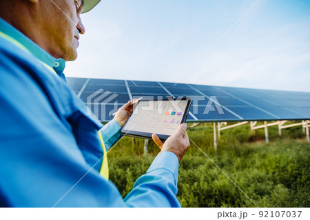 Engineer is holding tablet. Settings of solar system. Alternative energy concept 92107037
