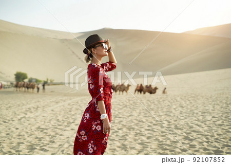 asian woman in red dress looking at view in desert with huge sand dunes in background 92107852