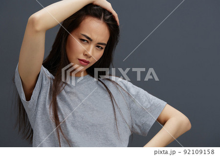 woman with long hair in a gray T-shirt gesturing with hands studio model 92109158