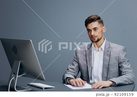 businessmen in a gray suit sits in front of a computer technologies businessmen in a gray suit sits in front of a computer technologies 92109159