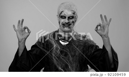 Creepy man Halloween zombie showing Ok gesture, like sign positive something good, smiles terribly Creepy man Halloween zombie showing Ok gesture, like sign positive something good, smiles terribly 92109459