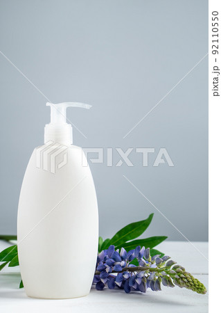 Cosmetic bottle with lotion and lupine flowers on gray background. Cosmetic bottle with lotion and lupine flowers on gray background. 92110550