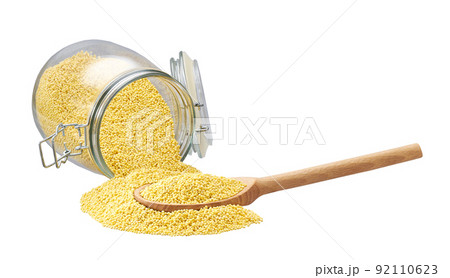 grains of millet in wooden scoop and in glass storage jar isolated on white background. grains of millet in wooden scoop and in glass storage jar isolated on white background. 92110623