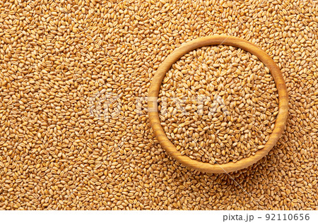 wooden plate with organic wheat on a wheat grains background close-up top view. 92110656