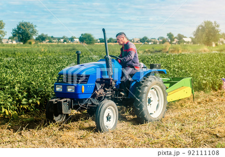 Middle-aged farmer on a tractor. Work on agricultural machinery on the field. Harvest potatoes. Farm and small business. Support and subsidies. Concessional lending and loans. 92111108