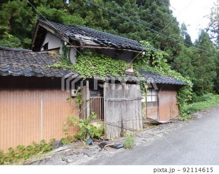 山間地で放置され草が生い茂り崩れかかっている空き家｜社会問題 92114615
