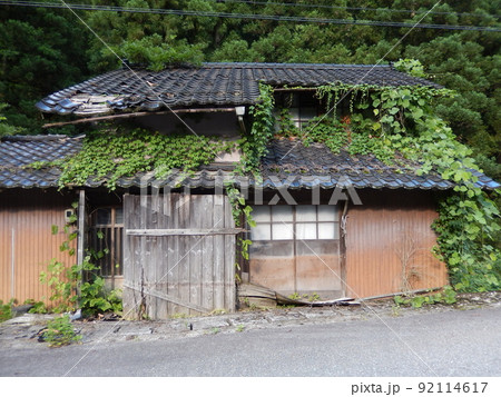 山間地で放置され草が生い茂り崩れかかっている空き家｜社会問題 92114617