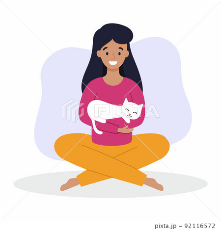 A girl holds a cat in her arms. A woman with a cat is sitting on the floor. Owner and pet. A girl holds a cat in her arms. A woman with a cat is sitting on the floor. Owner and pet. 92116572