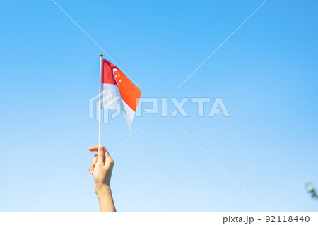 hand holding Singapore flag on blue sky background. Singapore National Day and happy celebration concepts hand holding Singapore flag on blue sky background. Singapore National Day and happy celebration concepts 92118440