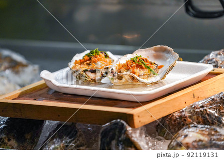 Fresh Raw big couple Oysters on the foam dish and wooden plate topping by fried garlic and leaf the ready to serve. Fresh Raw big couple Oysters on the foam dish and wooden plate topping by fried garlic and leaf the ready to serve. 92119131