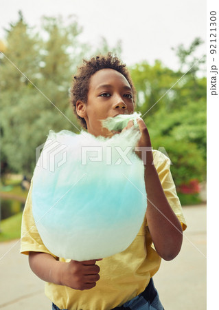 Boy eating cotton candy outdoors Boy eating cotton candy outdoors 92121300