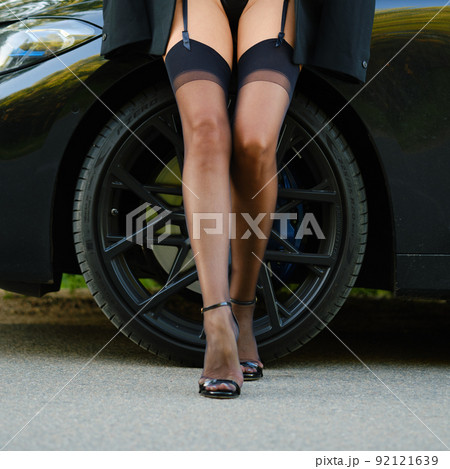 Female legs in stockings with garter belt near the car 92121639