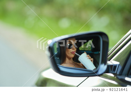 Reflection of woman in rear view mirror of a car Reflection of woman in rear view mirror of a car 92121641