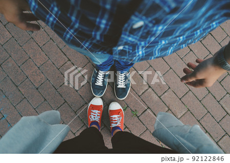 Photo of the legs of a man and a woman in blue and red sneakers with white laces on a paved path Photo of the legs of a man and a woman in blue and red sneakers with white laces on a paved path 92122846