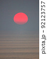 The sun is falling into the sea and being partially swallowed by the fog.  sky  is dark 92123757