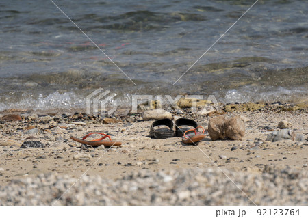 Travelers take off casual shoes on the beach by the sea to swim. Travelers take off casual shoes on the beach by the sea to swim. 92123764