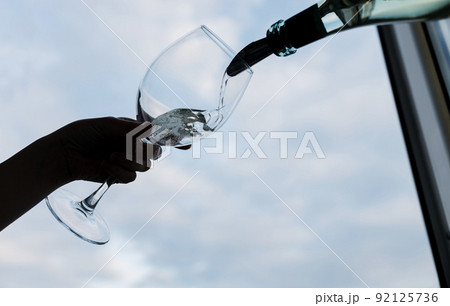 Girl pouring champagne into glass Girl pouring champagne into glass 92125736