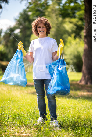Young volunteer with bags full of [plastic garbage Young volunteer with bags full of [plastic garbage 92126543