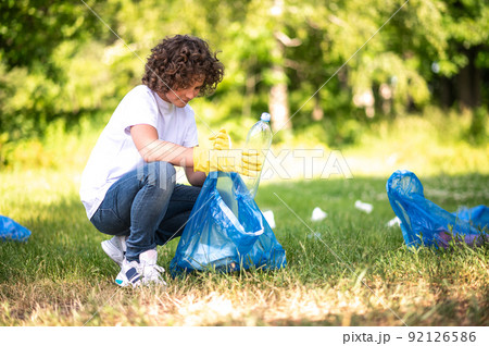 Young guy collecting and sorting garbage in the park 92126586
