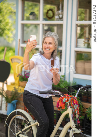 Cheerful woman on a bike eating ice-cream and looking happy 92127242