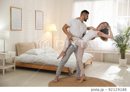 Lovely young couple dancing in bedroom at home Lovely young couple dancing in bedroom at home 92129186