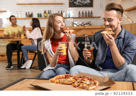 Young couple eating delicious pizza in cafe Young couple eating delicious pizza in cafe 92129333