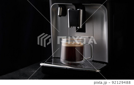 Freshly brewed coffee is poured from the coffee machine into glass cups. Freshly brewed coffee is poured from the coffee machine into glass cups. 92129488