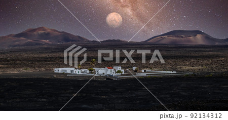Amazing nocturnal panoramic landscape of volcano craters in Timanfaya national park. Full moon over La Gueria, Lanzarote island, Canary islans, Spain. Artistic night sky picture 92134312