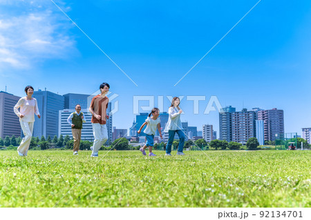 公園を駆けっこをする家族三世代 92134701
