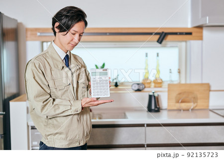 電卓を持つ作業服姿の営業マン 92135723