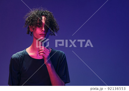 Relaxed stylish awesome curly man in black t-shirt posing isolated on color pink blue studio background. Cool fashion offer. Virtual Reality New Collection concept. Copy space for ad Relaxed stylish awesome curly man in black t-shirt posing isolated on color pink blue studio background. Cool fashion offer. Virtual Reality New Collection concept. Copy space for ad 92136553