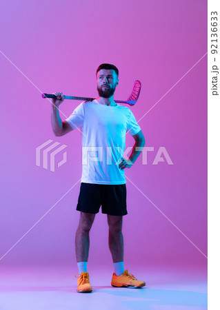 One sportive man, floorball player with floorball stick training isolated on lilac color background in neon. Sport, action and motion, movement, healthy lifestyle 92136633