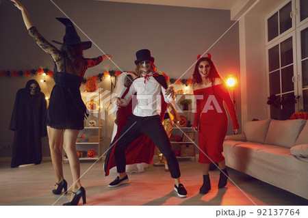 Happy young friends dancing and having fun together at festive party on Halloween night 92137764