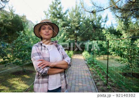 Portrait of a confident woman, farmer, gardener in an organic farm. Horticulturist, agricultural hobby, agribusiness.  92140302
