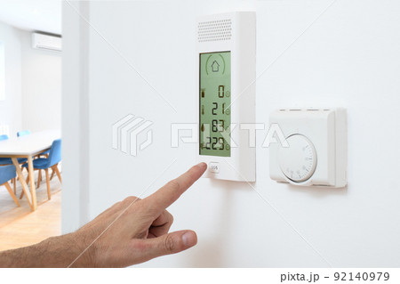 Hand activates burglar alarm control panel on wall in home office workplace interior Hand activates burglar alarm control panel on wall in home office workplace interior 92140979