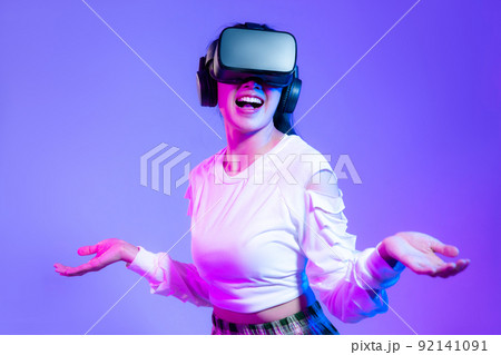 Metaverse concept, young asian girl in white fashion sweatshirt wearing vr headset playing touching and enjoying online game on purple background.. Metaverse concept, young asian girl in white fashion sweatshirt wearing vr headset playing touching and enjoying online game on purple background.. 92141091
