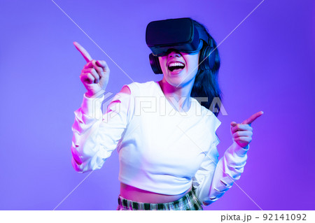 Metaverse concept, young asian girl in white fashion sweatshirt wearing vr headset playing touching online game purple background.. 92141092