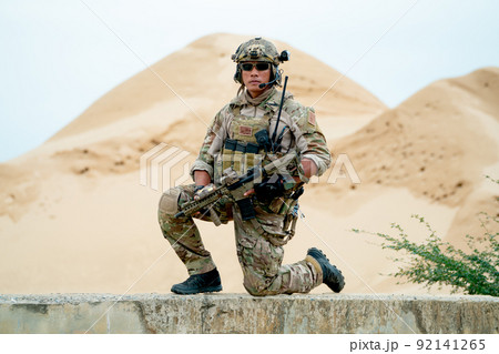 Soldier or military man sit with guarded position and look at camera in area look like desert Soldier or military man sit with guarded position and look at camera in area look like desert 92141265