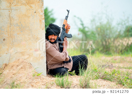 Terrorist man with black veil stay behind of concrete wall also hold gun to prepare for fight Terrorist man with black veil stay behind of concrete wall also hold gun to prepare for fight 92141270