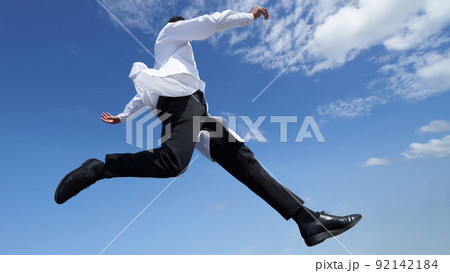 青空のもとジャンプする白衣姿の男性 92142184