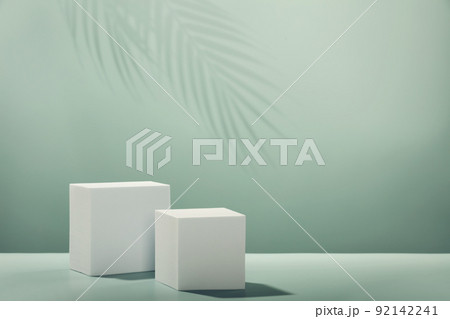 Abstract empty white podiums with leaves shadows on green background Abstract empty white podiums with leaves shadows on green background 92142241