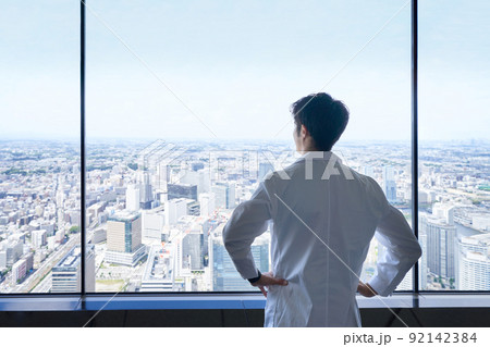 高所から街の全景を眺める白衣男性の後ろ姿 高所から街の全景を眺める白衣男性の後ろ姿 92142384
