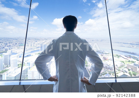 晴れた日に高所から街の全景を眺める白衣男性の後ろ姿 92142388